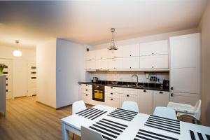 コウォブジェクにあるApartament SunSeaの白いキャビネット、テーブルと椅子付きのキッチンが備わります。