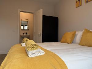a bedroom with two beds with yellow blankets and a mirror at Buxton Road Suites in London