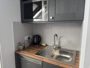 a kitchen with a sink and a microwave at Buxton Road Suites in London +23 photos