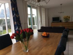 una mesa de comedor con un jarrón de tulipanes y naranjas. en Bungalow for 6 people near beach, en Sint Maartenszee