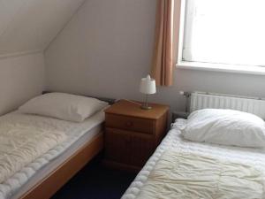 a bedroom with two beds and a table with a lamp at bungalow for 6 people, near the beach in Sint Maartenszee