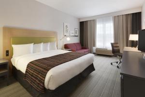 ein Hotelzimmer mit einem großen Bett und einem Stuhl in der Unterkunft Country Inn & Suites by Radisson, Wausau, WI in Schofield