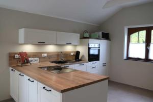 eine Küche mit weißen Schränken und einer Holzarbeitsplatte in der Unterkunft Ferienwohnung Weinbergsliebe in Rümmelsheim