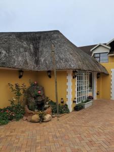 a yellow house with a thatched roof and a patio at Seaside Paradise in Kingsburgh