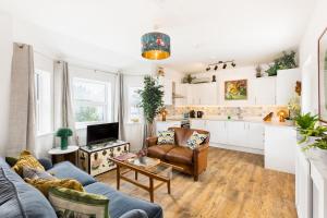 a living room with a couch and a kitchen at Queens Head Boutique Hotel Apartments in Gloucestershire