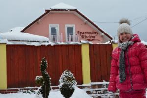 una mujer parada en la nieve frente a una casa en Apartmány Riviéra a Chalupa Riviéra Liptov, Bešeňová, en Bešeňová