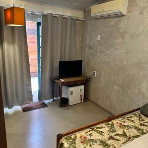 a room with a tv and a desk with a computer at Jardim Secreto Guest House in Búzios