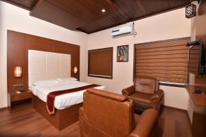 Un dormitorio con una cama, un sofá y una silla. en Garuda Luxury Bungalow, en Trichūr