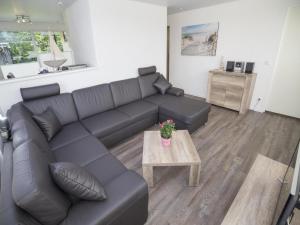 a living room with a black couch and a table at Sint Maartenszee Renovated Family Retreat in Sint Maartenszee