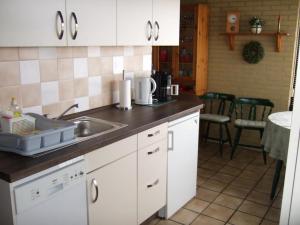 a kitchen with white cabinets and a sink at Bungalow in Wildrijk with Fenced Garden in Sint Maartenszee