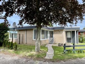 a house with a tree in front of it at Pet-friendly bungalow near Beach in Sint Maartenszee
