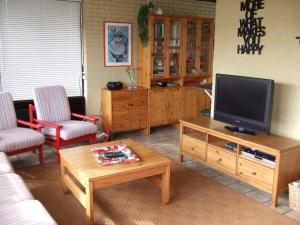 a living room with a television and a coffee table at Bungalow in Wildrijk with Fenced Garden in Sint Maartenszee