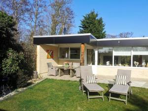 a patio with chairs and a table in a yard at Inviting bungalow with private garden in Sint Maartenszee