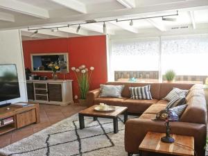 a living room with a couch and a tv at Inviting bungalow with private garden in Sint Maartenszee