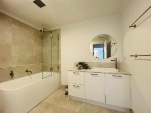 悉尼KozyGuru Camperdown Cozy 2-Bed Apt and Parking的带淋浴、水槽和镜子的浴室 更多5张照片