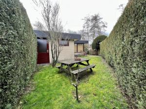 a picnic table in a yard between two large hedges at Bungalow for 4 people in Wildrijk in Sint Maartenszee