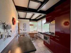 a kitchen with red cabinets and a table in it at Bungalow for 4 people in Wildrijk in Sint Maartenszee +20 photos