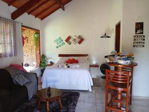 a bedroom with a white bed and a couch at Chalé monte verde com hidromassagem in Camanducaia