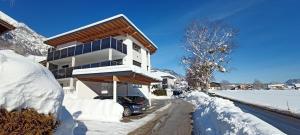 a house with a car parked in the snow at Apart Dahoam in Wiesing