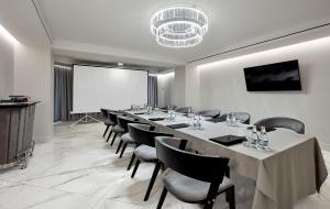 sala konferencyjna z dużym stołem i krzesłami oraz ekranem projekcyjnym w obiekcie Hotel Maria w mieście Dębno Polskie