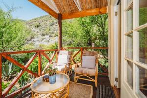 a screened in porch with two chairs and a table at De Poort Country Lodge in Oudtshoorn