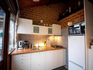 a kitchen with white cabinets and a white refrigerator at Bungalow in Sint Maartenszee near dune in Sint Maartenszee