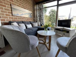 a living room with a couch and chairs and a tv at Bungalow in Sint Maartenszee near dune in Sint Maartenszee
