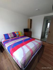 un lit avec une couette colorée dans une chambre dans l'établissement superapartamento GIRADOT-RICAURTE, à San Rafael