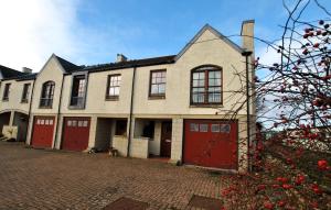 a large house with red doors on a brick driveway at Seabreeze- stylish coastal home Crail in Crail