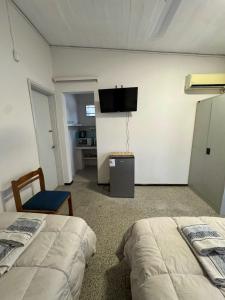 ein Schlafzimmer mit zwei Betten und einem Fernseher an der Wand in der Unterkunft Luminoso y Acogedor Espacio in Paysandú