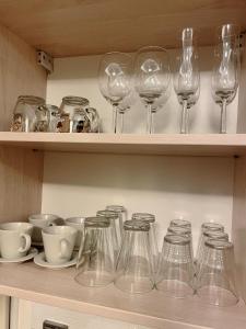 een rij wijnglazen en kommen op een plank bij No̱410 City View Apartment & free private parking in Krakau +8 foto's
