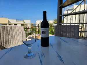 eine Flasche Wein und ein Glas auf dem Tisch in der Unterkunft Tranquil Penthouse Apartment Turtle Bay Village Esentepe in Ayios Yeoryios