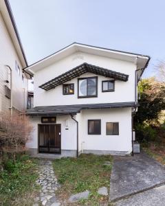 a white house with black doors and a driveway at 篝-Kagari- in Hakone