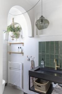 La salle de bains est pourvue d'un lavabo noir et de carrelage vert. dans l'établissement Villa Magnolia, à Bergen