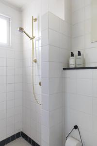 une salle de bain carrelée blanche avec douche et toilettes dans l'établissement Villa Magnolia, à Bergen 20 autres photos