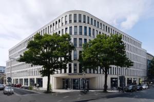 a large white building with trees in front of it at Urban Pearl Hannover in Hannover