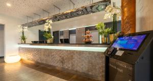 a lobby with a bar with plants on the counter at PLAZA INN Stuttgart-Ditzingen in Ditzingen