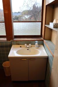 a bathroom with a sink and a window at Sanju 燕三条古民家の宿 in Sanjo