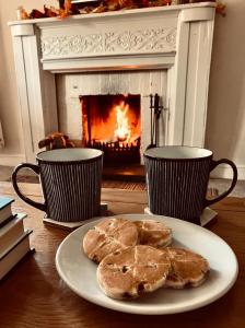a plate of cookies on a table in front of a fireplace at Courtyard Cottage with hot tub and walled garden in Hubberston