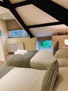 a bedroom with two beds and two windows at Courtyard Cottage with hot tub and walled garden in Hubberston