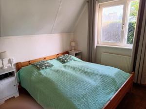 a bedroom with a bed with a green comforter and a window at Cozy holiday home in Sint Maartenszee in Sint Maartenszee
