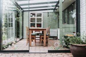 a patio with a table and chairs in a glass house at Huisje Mezengroet in Lanaken