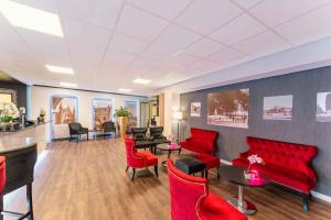 a waiting room with red chairs and tables at PLAZA Premium Den Haag City Center in The Hague