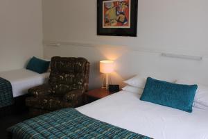 a hotel room with two beds and a chair at Motel Northview Mackay in Mackay