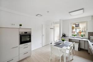 a white kitchen with a table and white chairs at MONTEUR - Unterkunft für bis zu 5 Personen in 63452 Hanau - HU08b in Hanau am Main