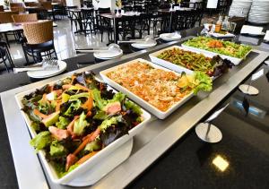 three plates of food on a table with salads at Hotel Rainha dos Apóstolos in Aparecida