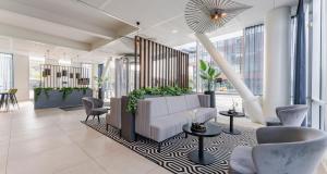 a lobby with a couch and chairs and windows at PLAZA Premium Almere in Almere
