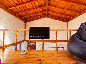 a living room with a flat screen tv on a wooden floor at Panchwati Farms Homestay in Almora