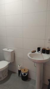 a white bathroom with a toilet and a sink at Residencial Bambu in Garopaba