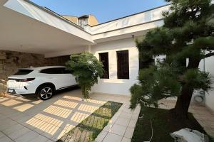 a white car parked in front of a white house at 0001 - Pousada HG quarto home office, duplo in Vila Gopoúva